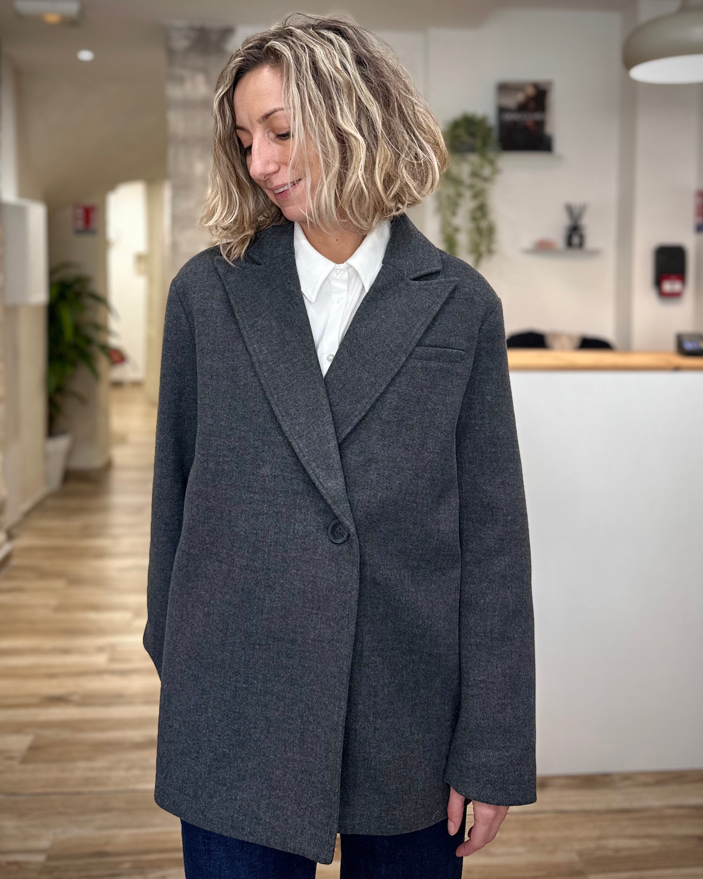 Femme portant un manteau gris droit sur chemise blanche
