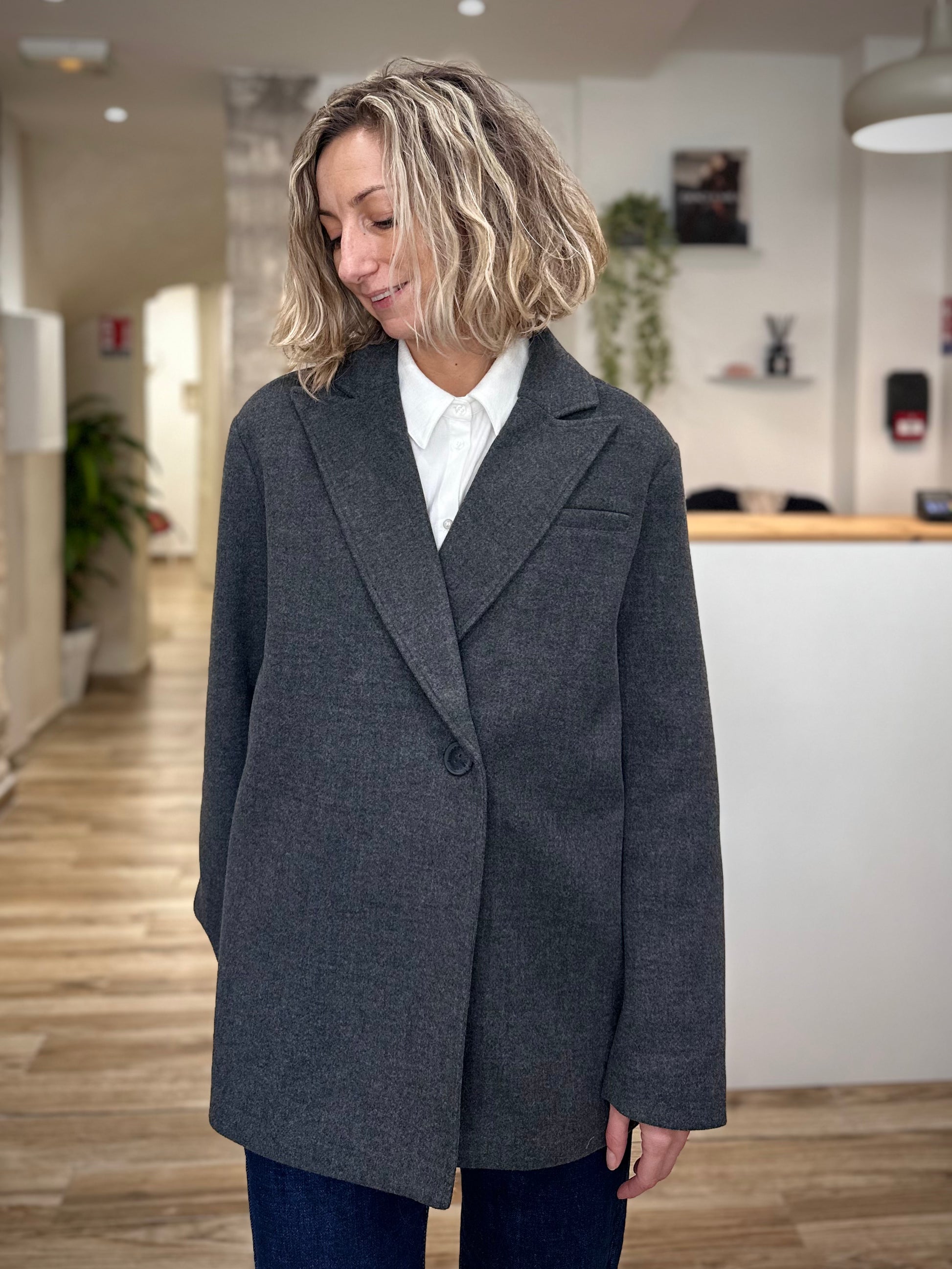 Femme portant un manteau gris droit sur chemise blanche
