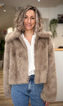 Femme portant un manteau court en fausse fourrure greige