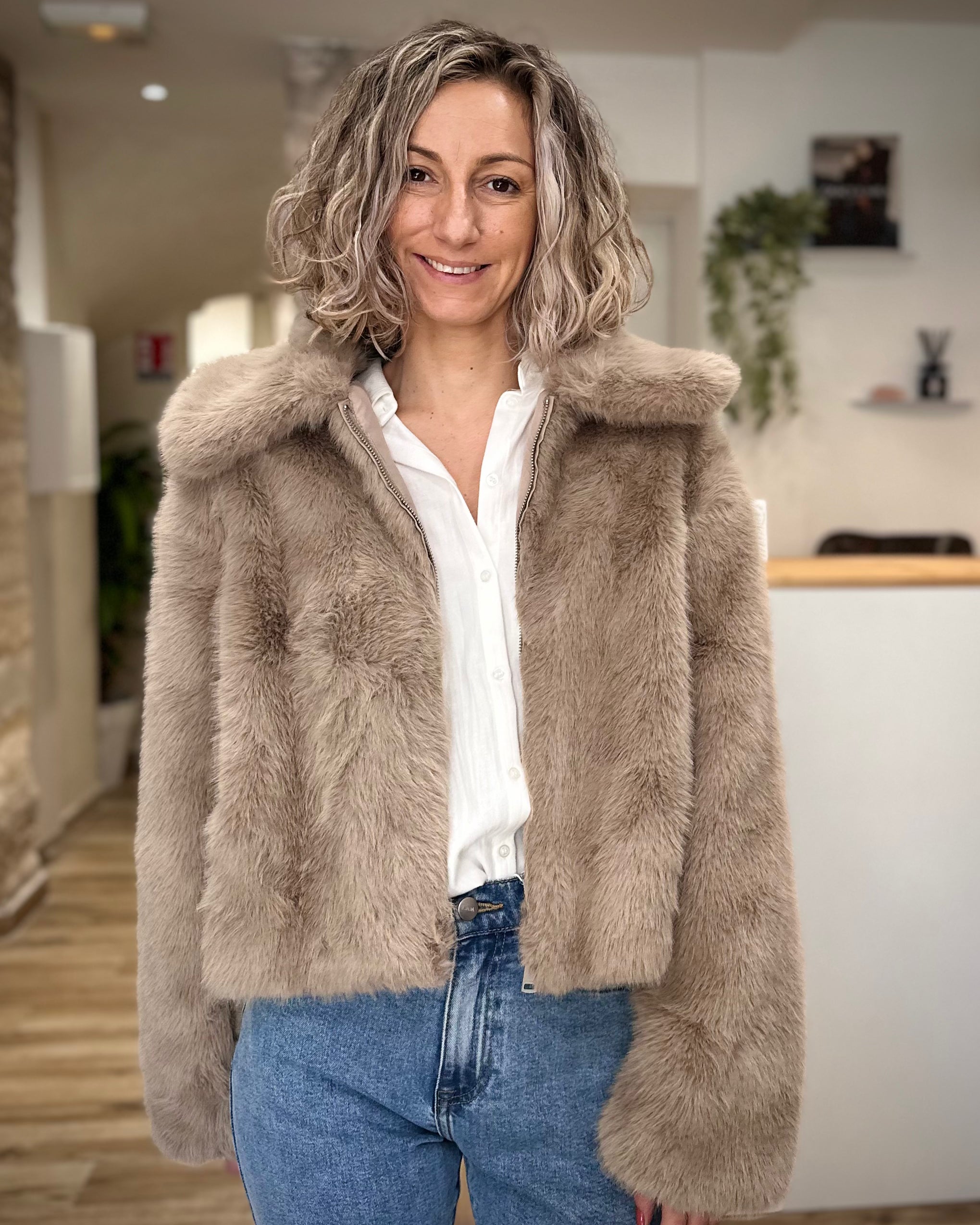 Femme portant un manteau court en fausse fourrure greige