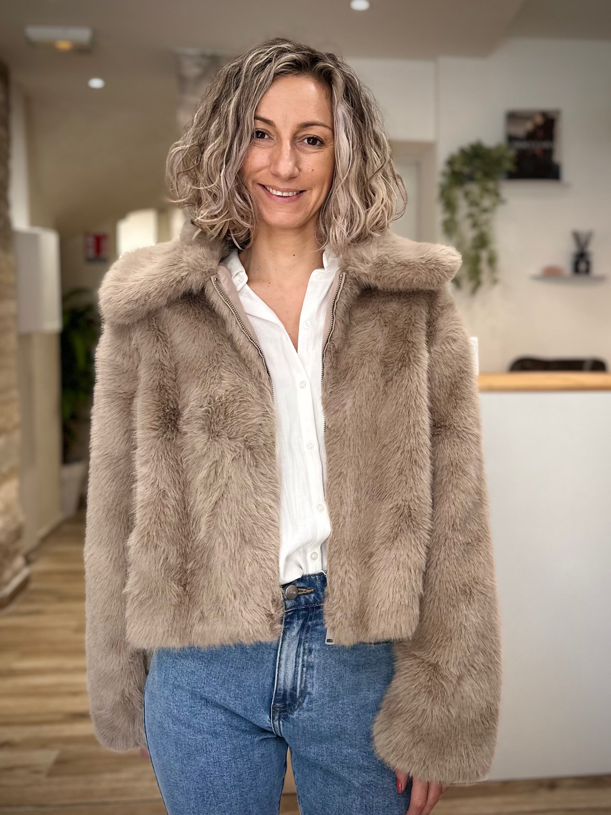 Femme portant un manteau court en fausse fourrure greige