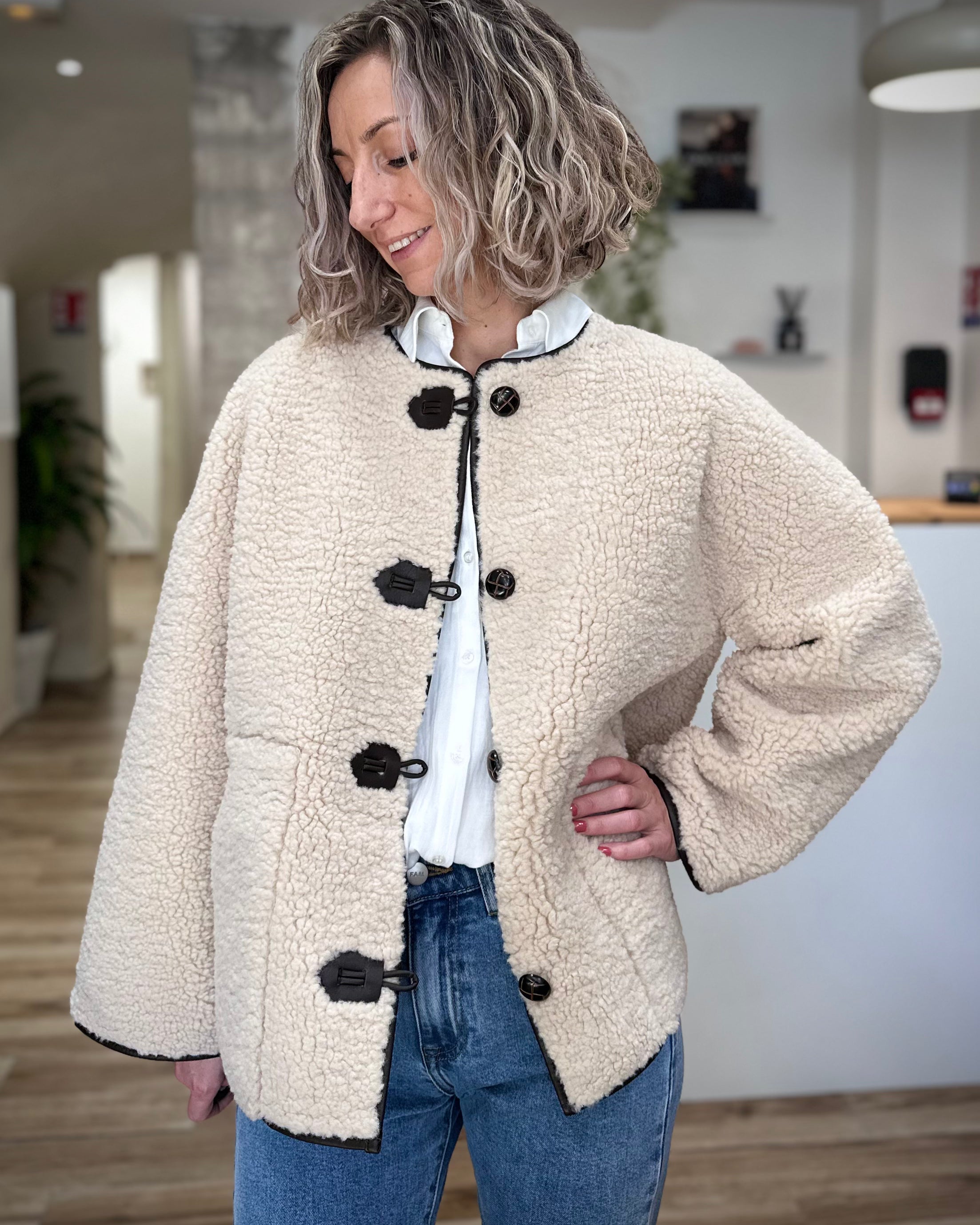 Femme portant un manteau oversize en faux shearling écru