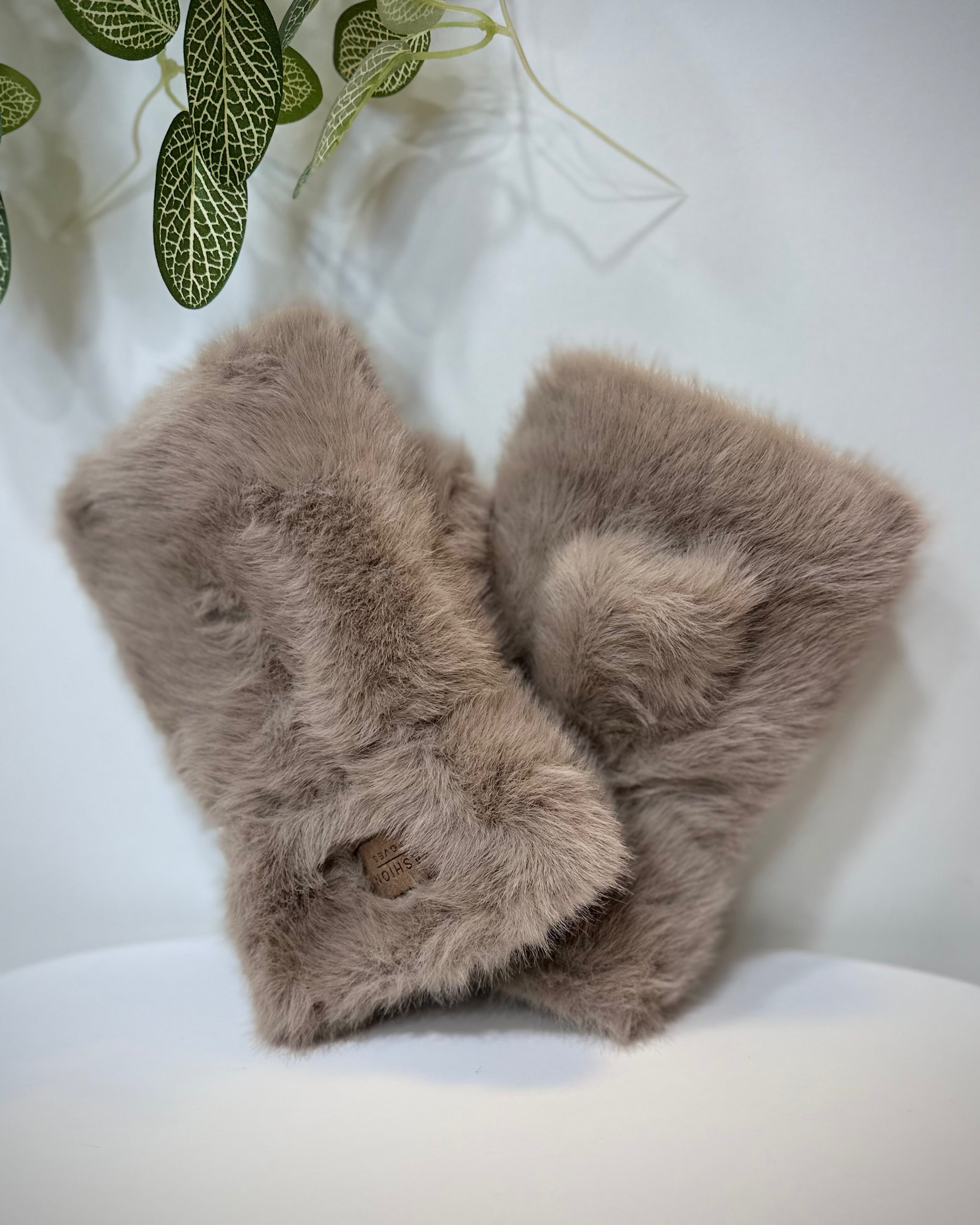 Mitaines femme fausse fourrure taupe posées sur une table