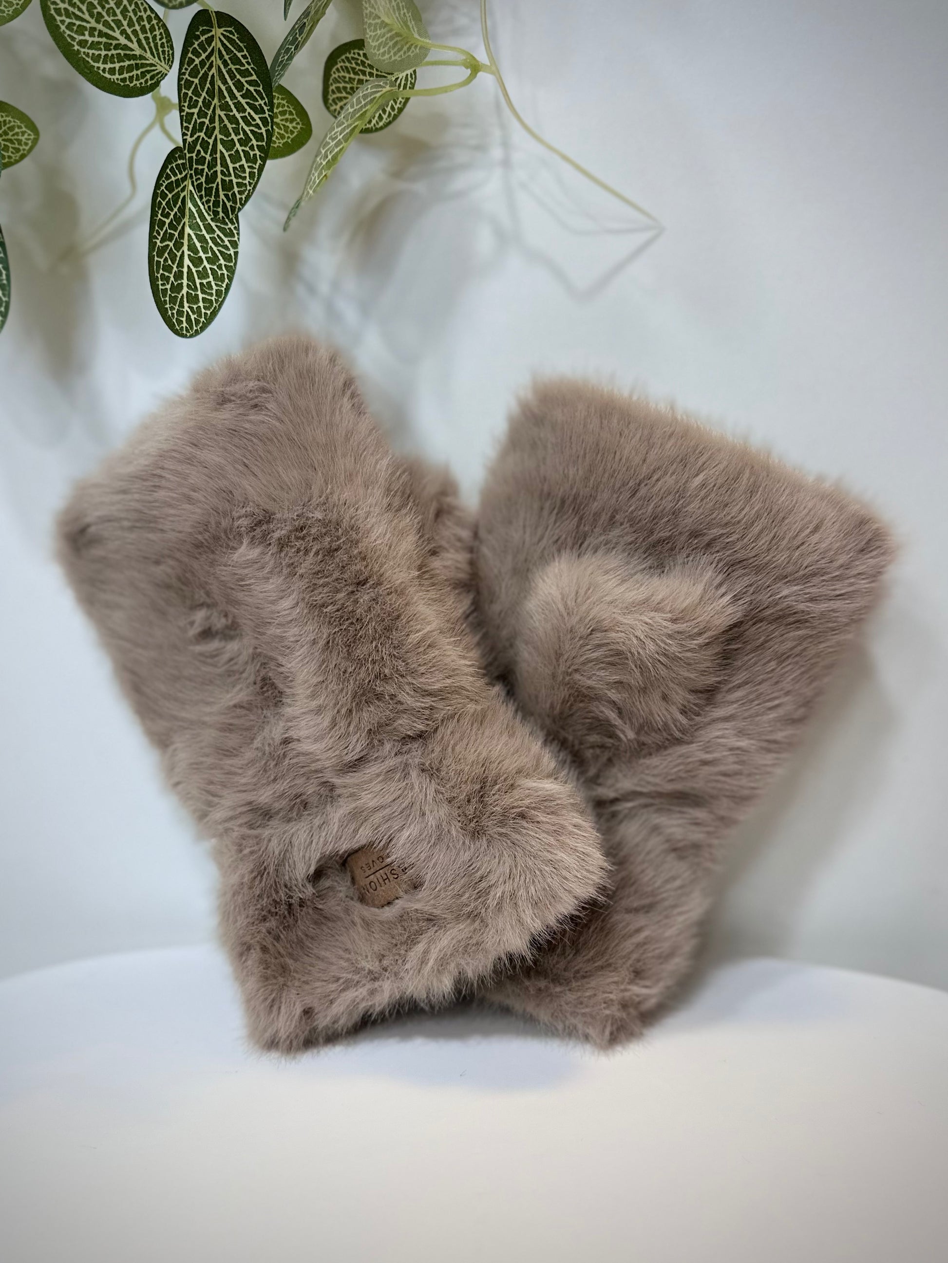 Mitaines femme fausse fourrure taupe posées sur une table