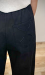 Gros plan sur la croix brodée main au dos d’un pantalon coton