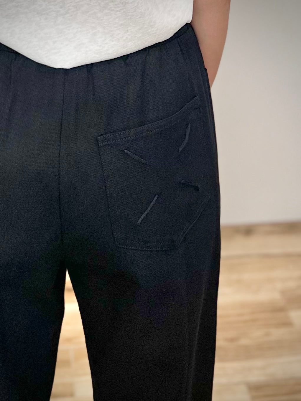 Gros plan sur la croix brodée main au dos d’un pantalon coton