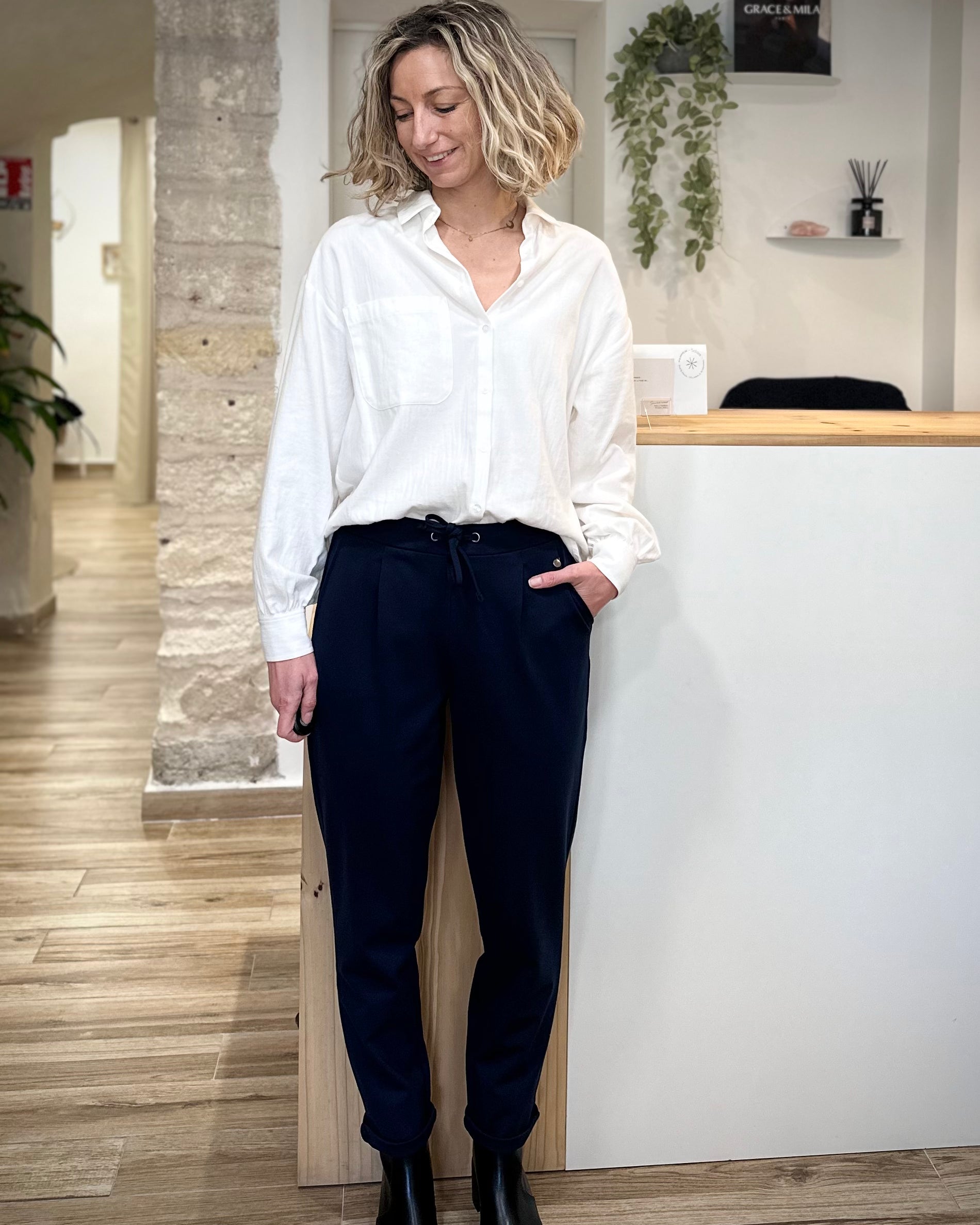 Femme portant un pantalon bleu marine fuselé avec chemise blanche