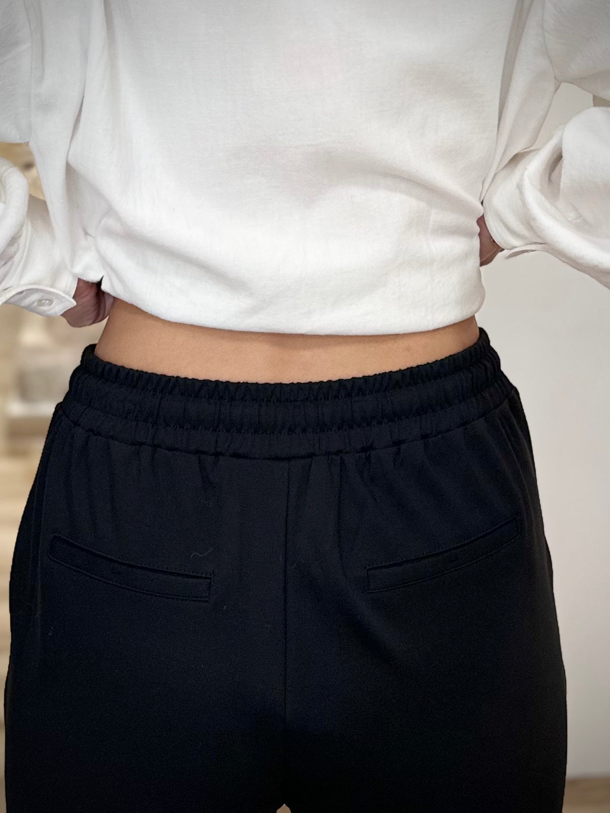 Fausse poche passepoilée à l’arrière d’un pantalon noir