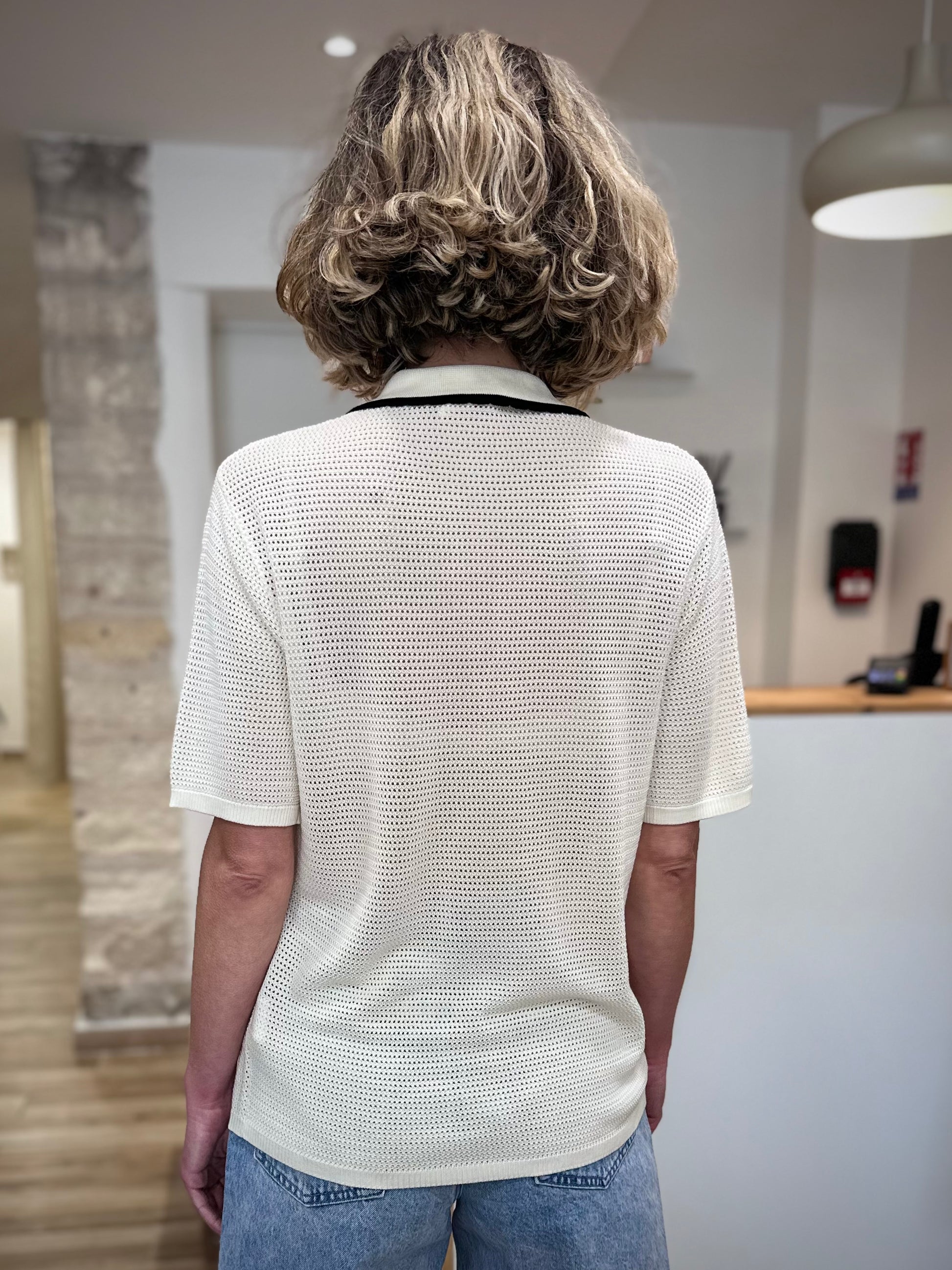 Femme de dos portant un polo maille légère ajourée 