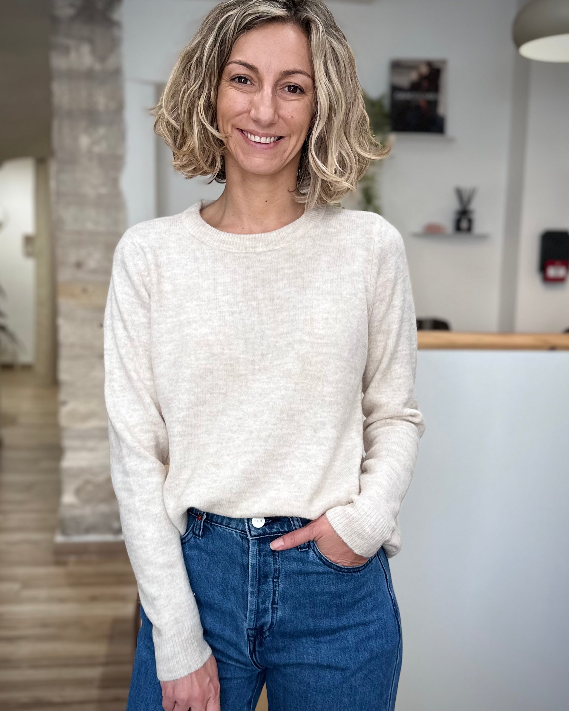 Femme portant un pull beige chiné à manches ajustées