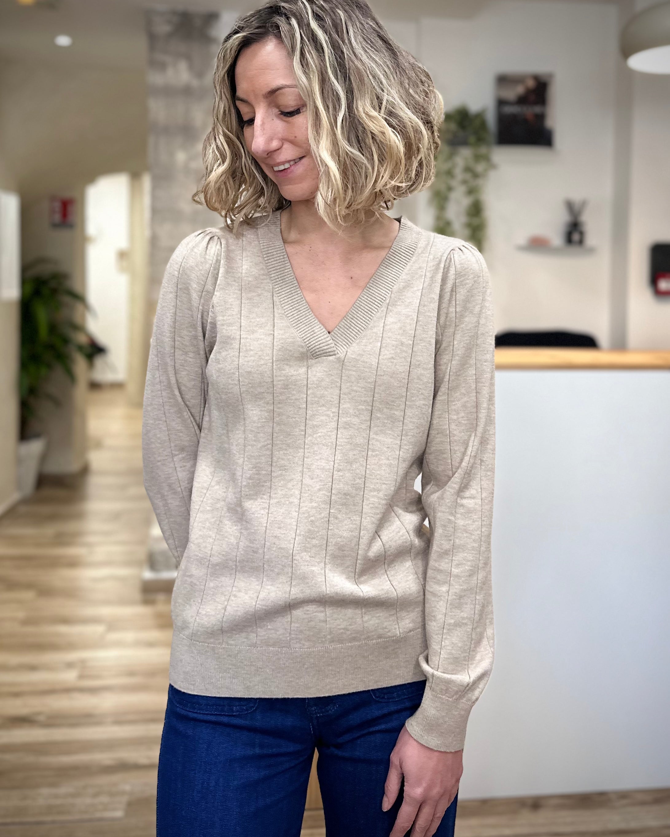 Femme portant un pull beige col V coupe droite