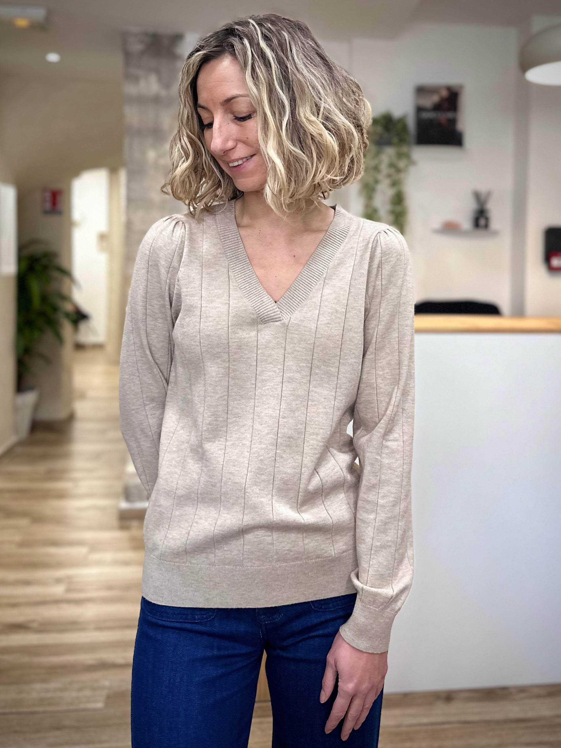 Femme portant un pull beige col V coupe droite