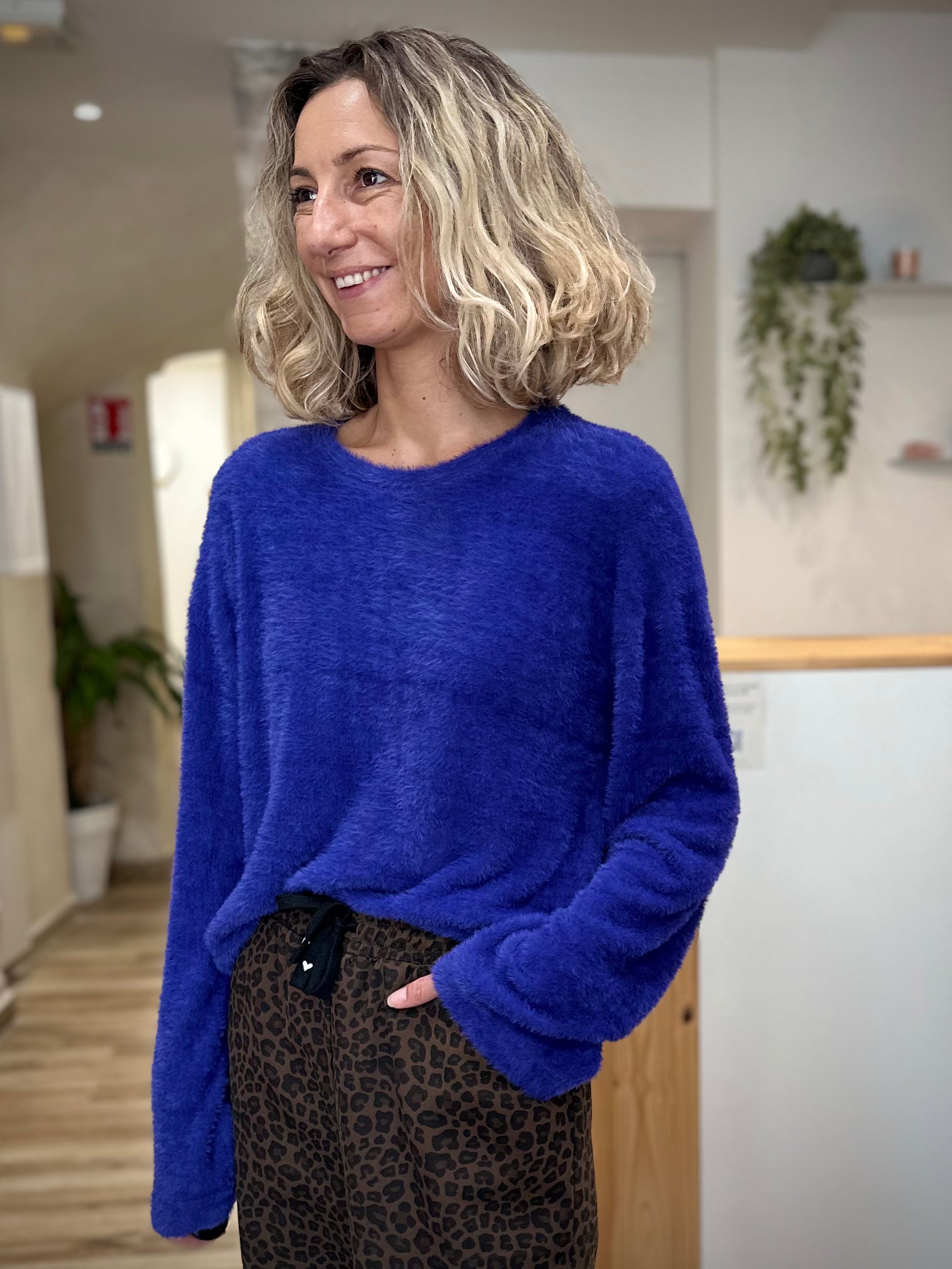 Femme portant un pull bleu confortable avec manches évasées