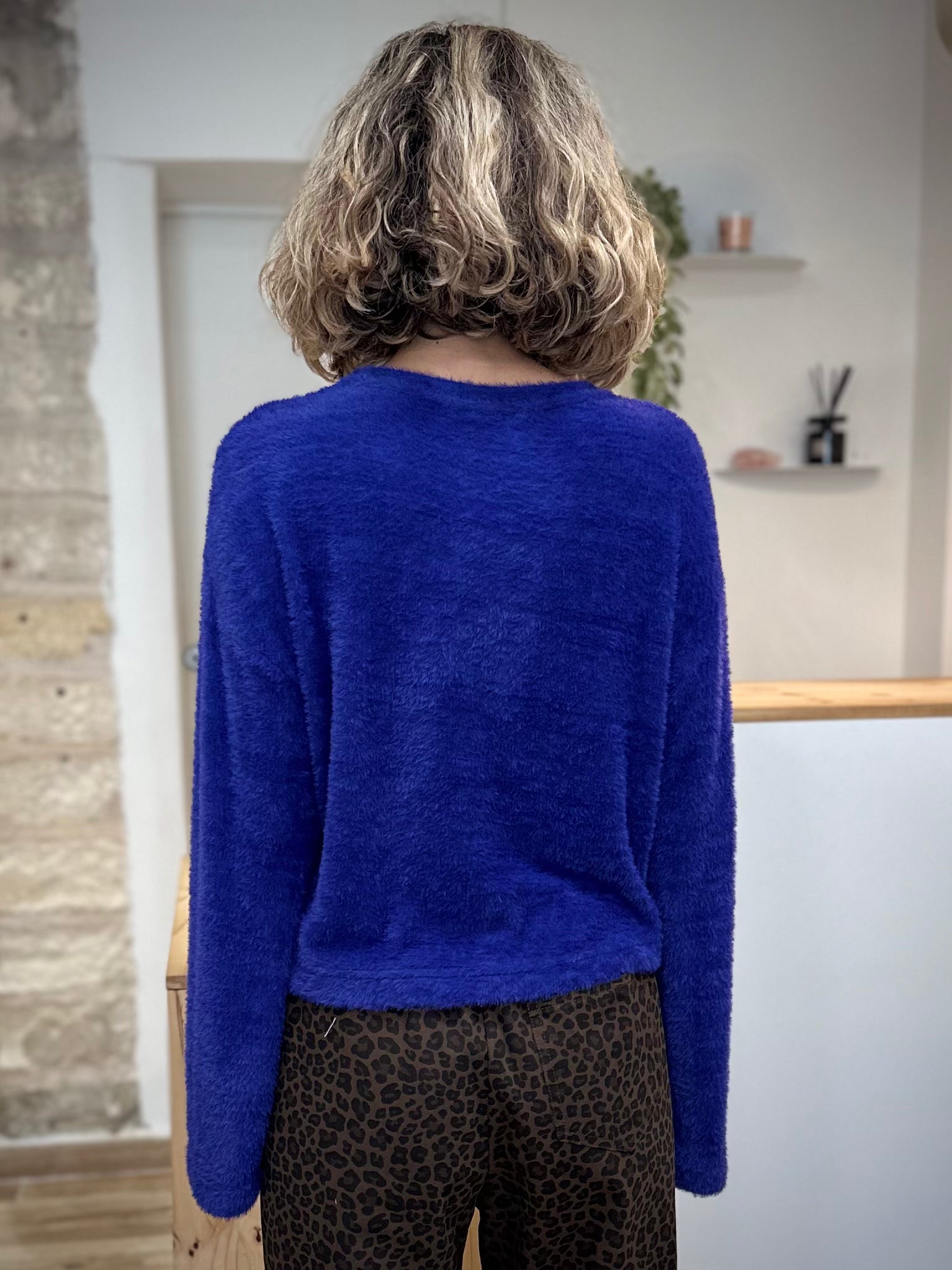 Silhouette de dos femme portant un pull bleu à manches évasées
