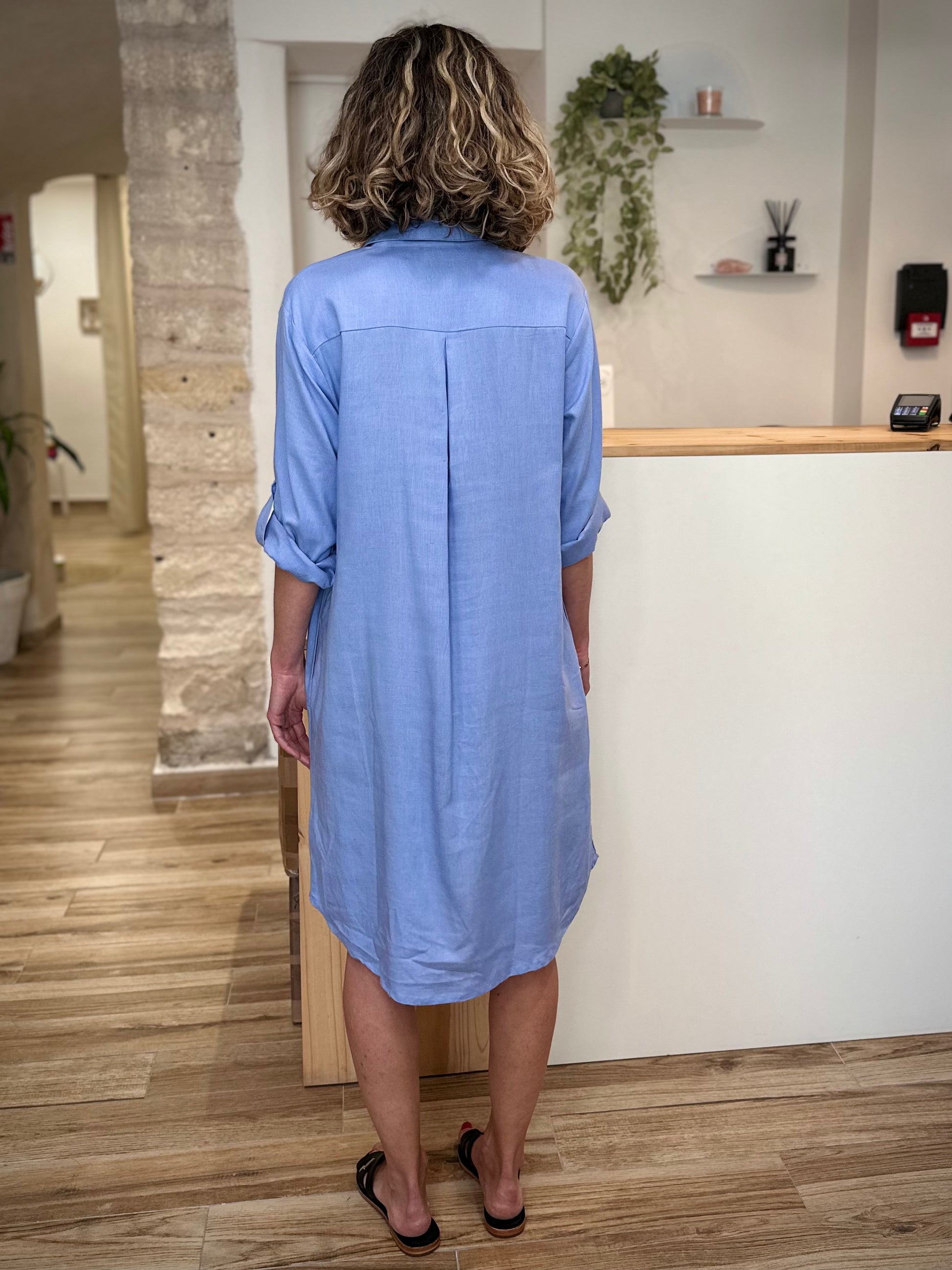 Silhouette féminine en robe fluide bleu pastel de dos