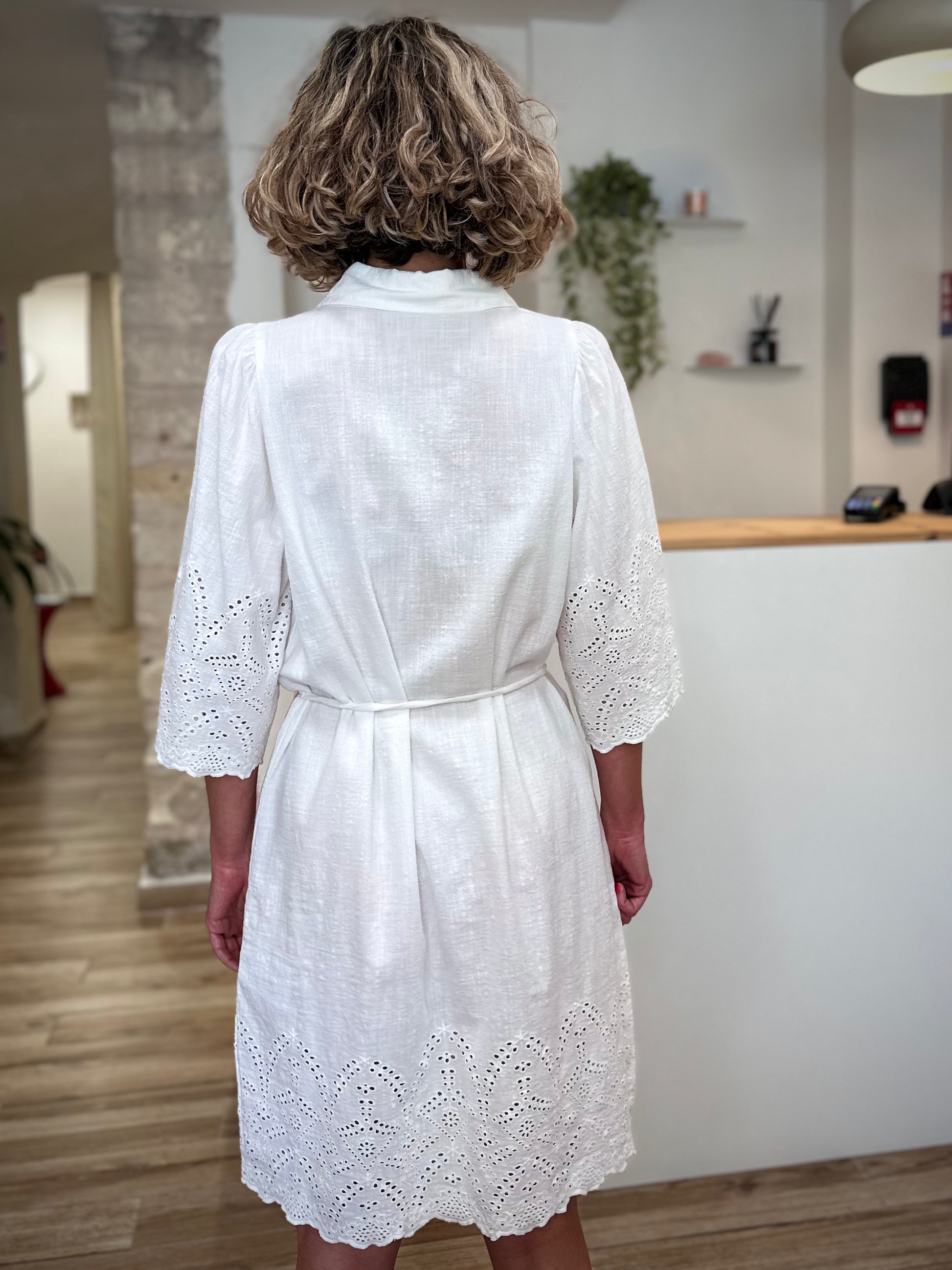Femme de dos portant une robe brodée blanche en coton naturel 