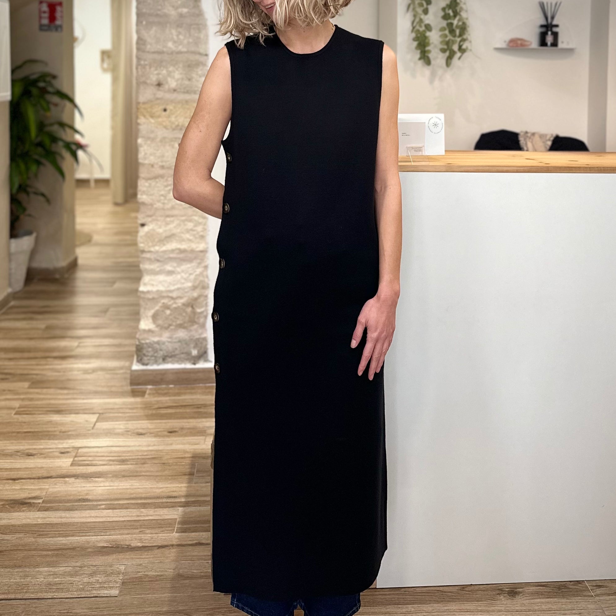 Femme portant une robe longue noire droite avec boutons latéraux