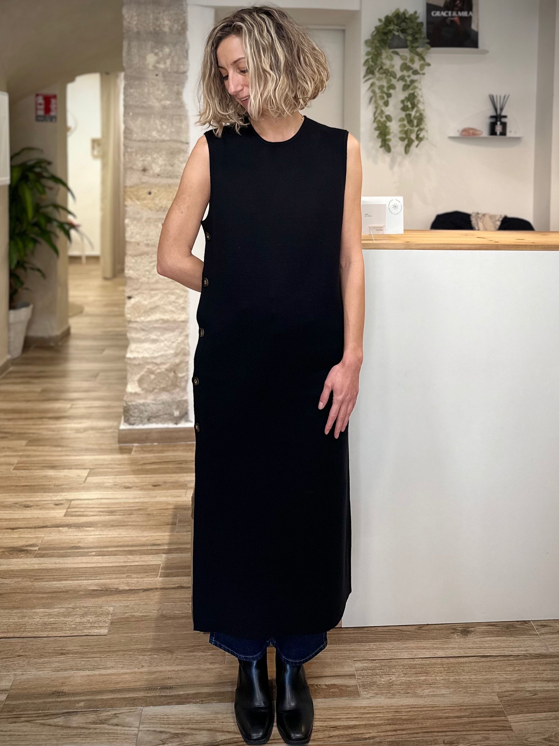 Femme portant une robe longue noire droite avec boutons latéraux