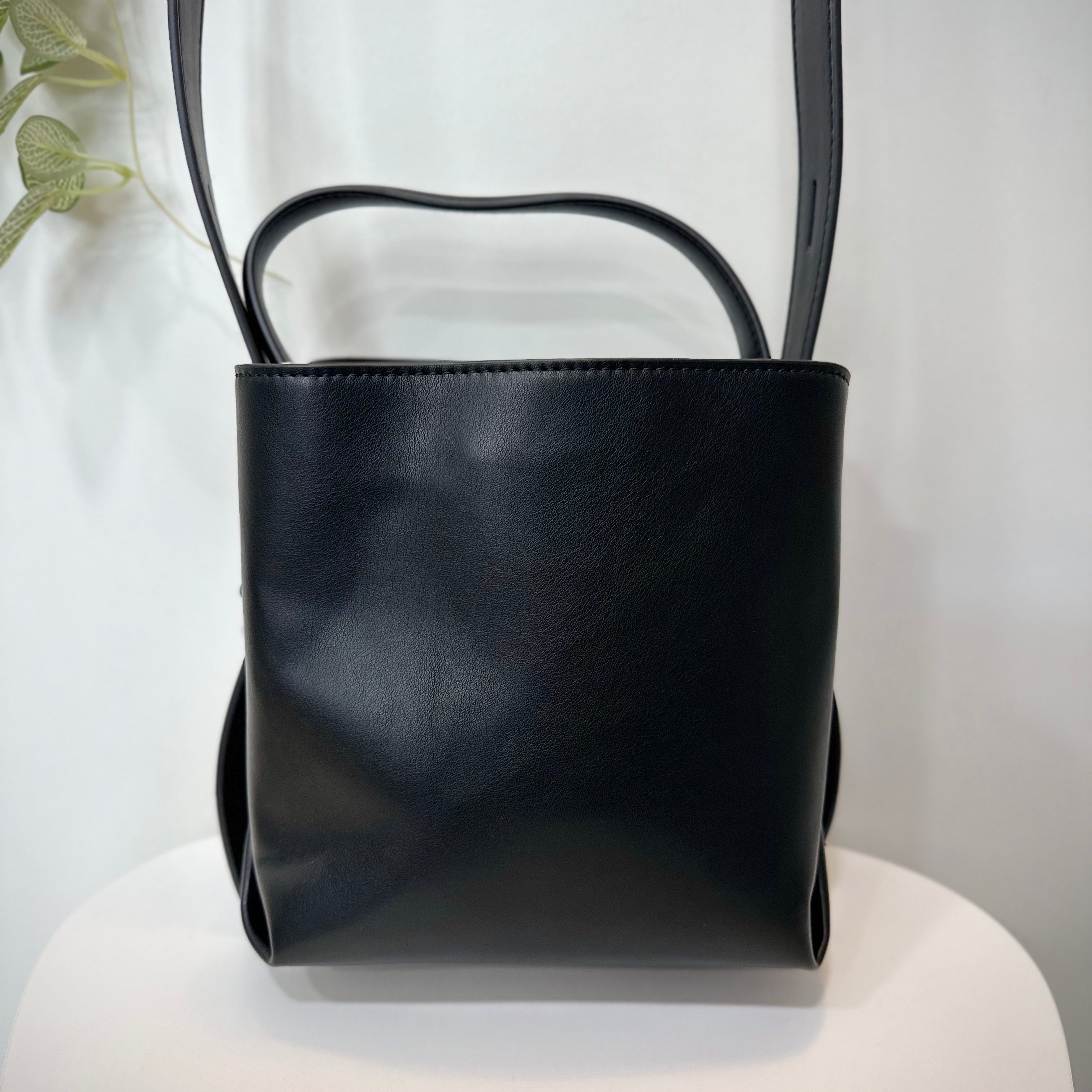 Sac HVISK noir posé sur une chaise en bois blanc
