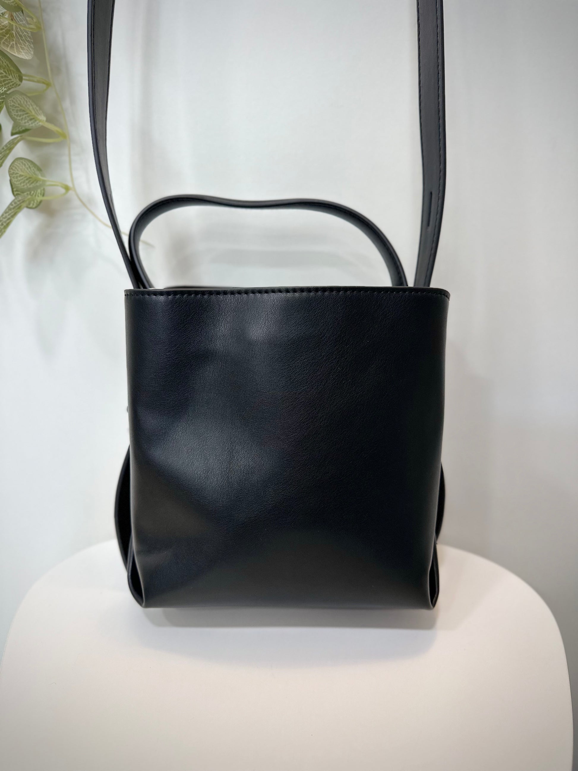 Sac HVISK noir posé sur une chaise en bois blanc