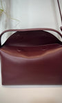Gros plan sur le rabat magnétique du sac bordeaux
