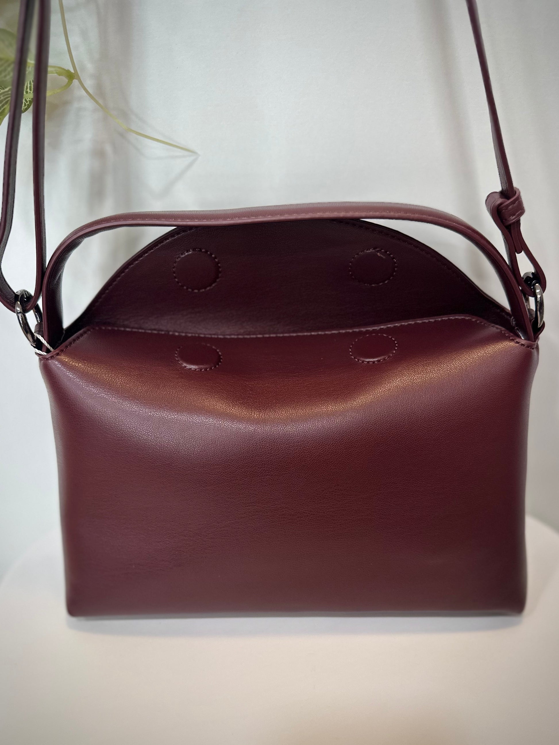 Gros plan sur le rabat magnétique du sac bordeaux