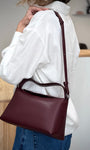 Femme portant un sac à main vegan bordeaux à l’épaule