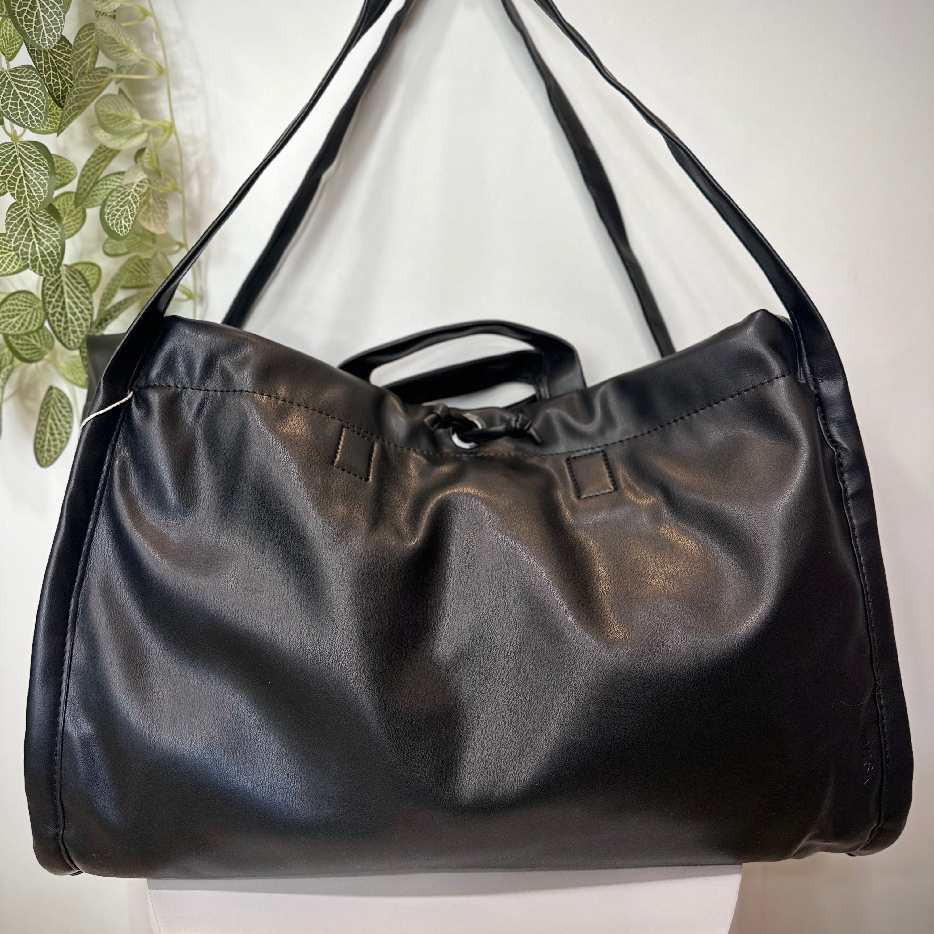 Sac SAGE noir posé sur un tabouret en bois clair
