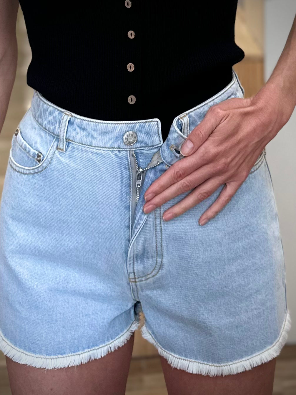 Détail du bouton métallique du short denim