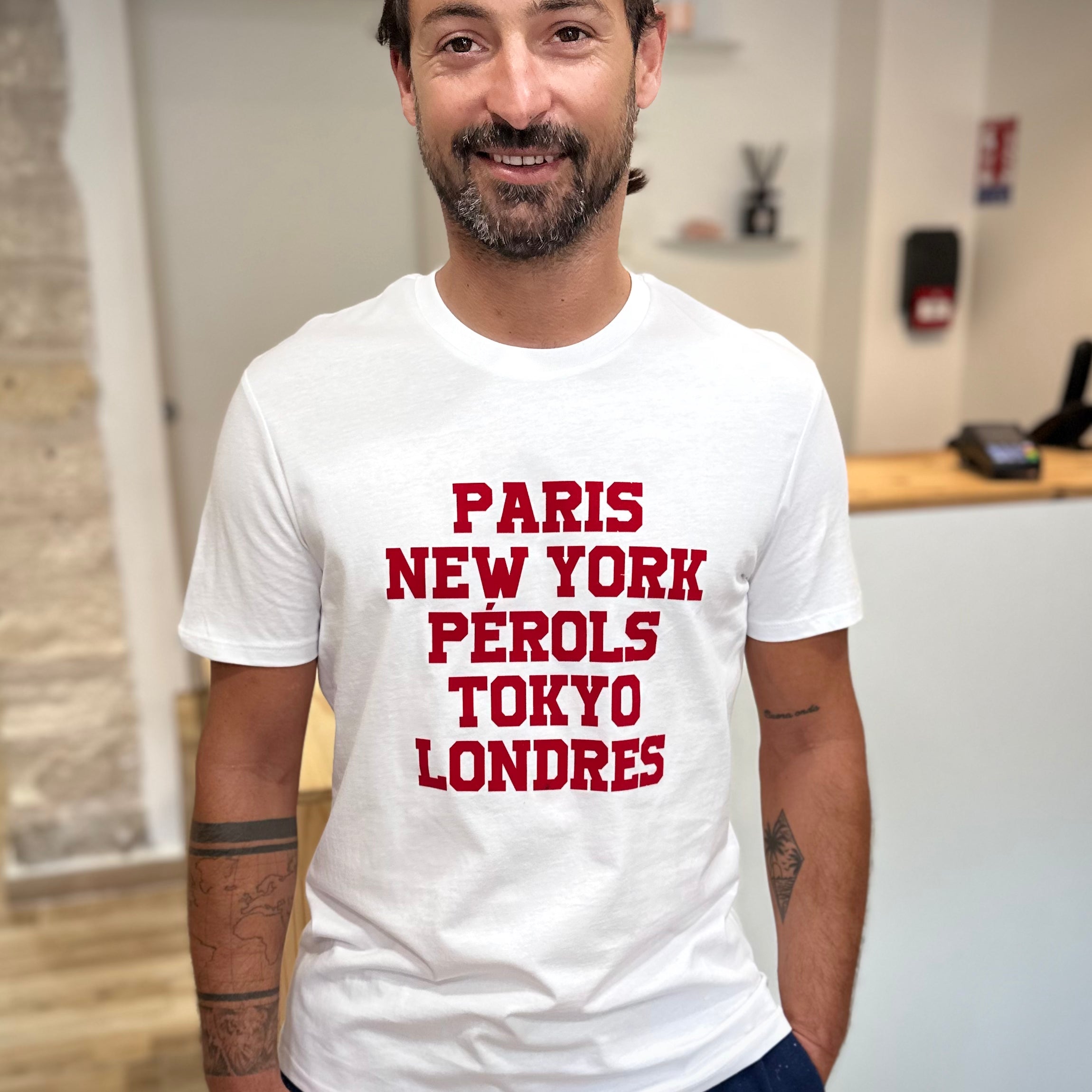 Homme portant un tee-shirt blanc imprimé rouge Paris New-York Pérols Tokyo Londres