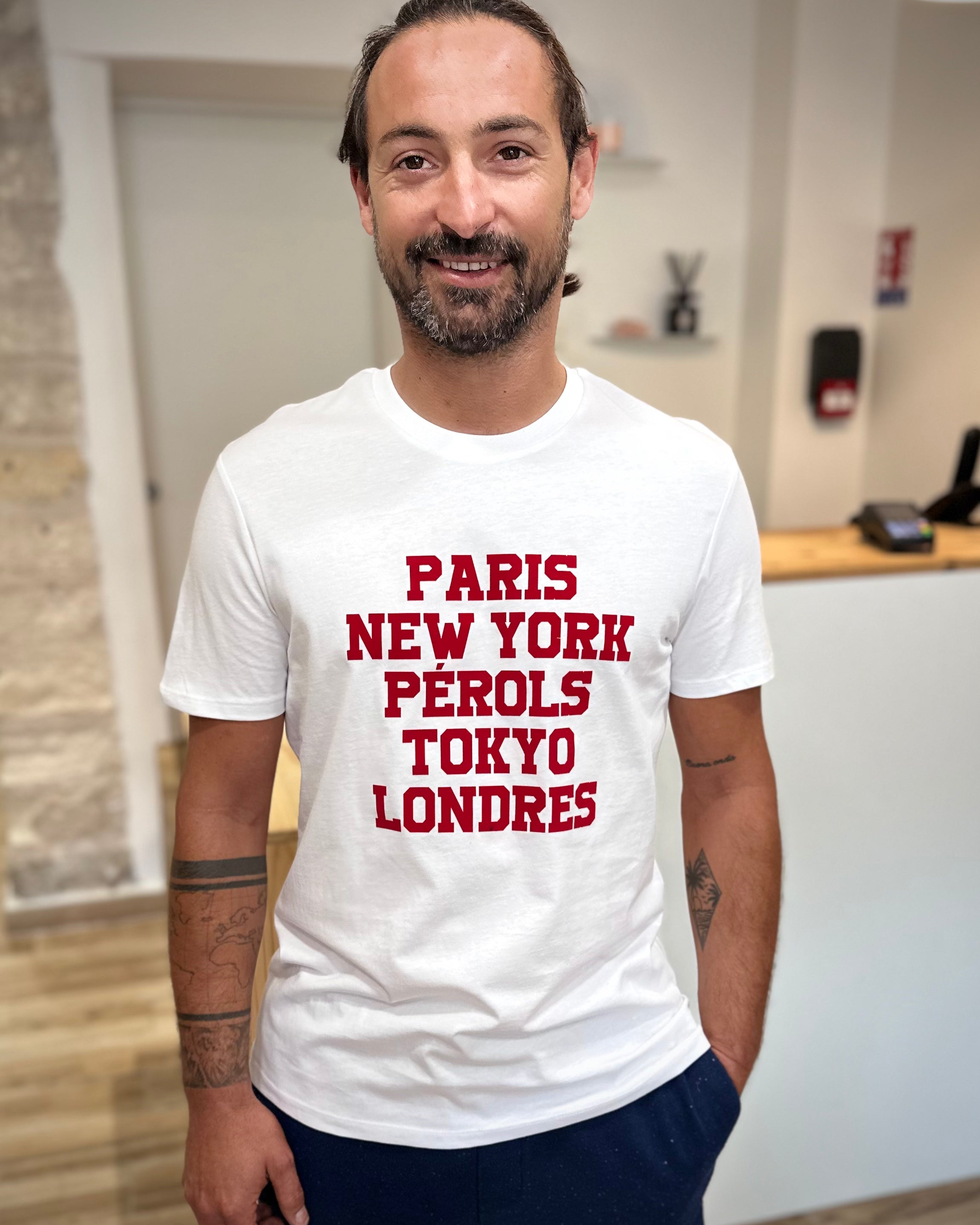 Homme portant un tee-shirt blanc imprimé rouge Paris New-York Pérols Tokyo Londres