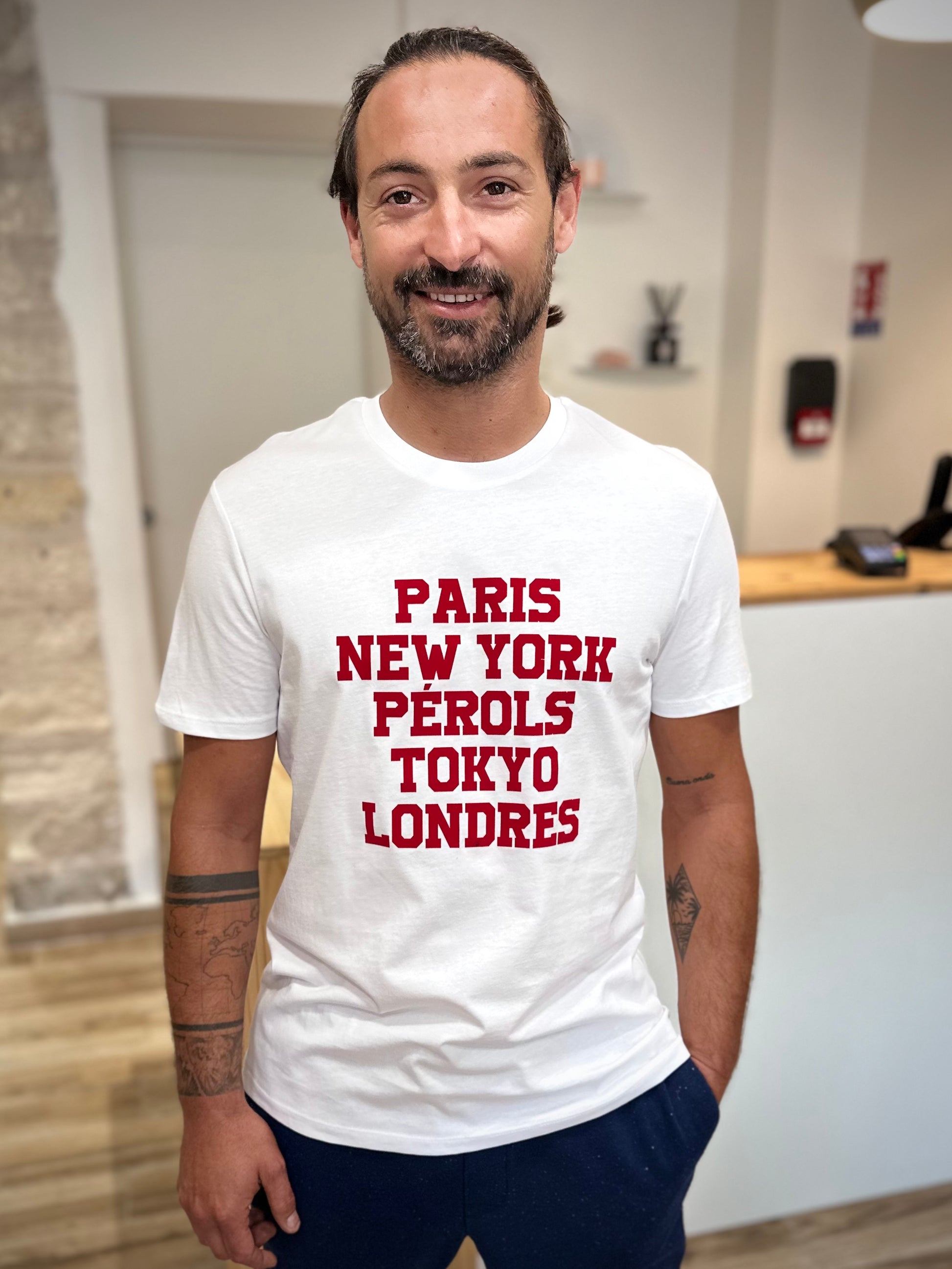 Homme portant un tee-shirt blanc imprimé rouge Paris New-York Pérols Tokyo Londres