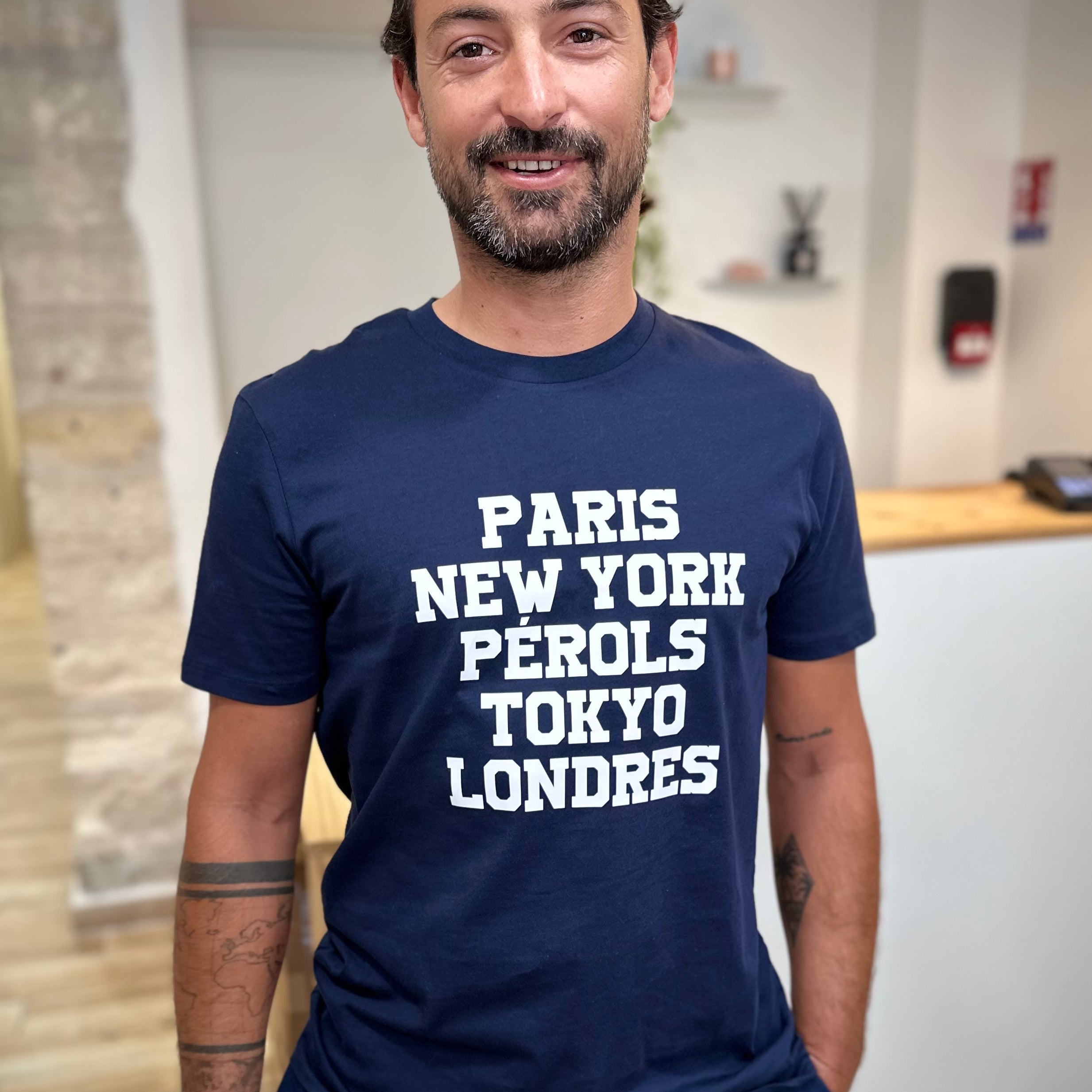 Homme portant un tee-shirt bleu marine imprimé blanc Paris New-York Pérols Tokyo Londres