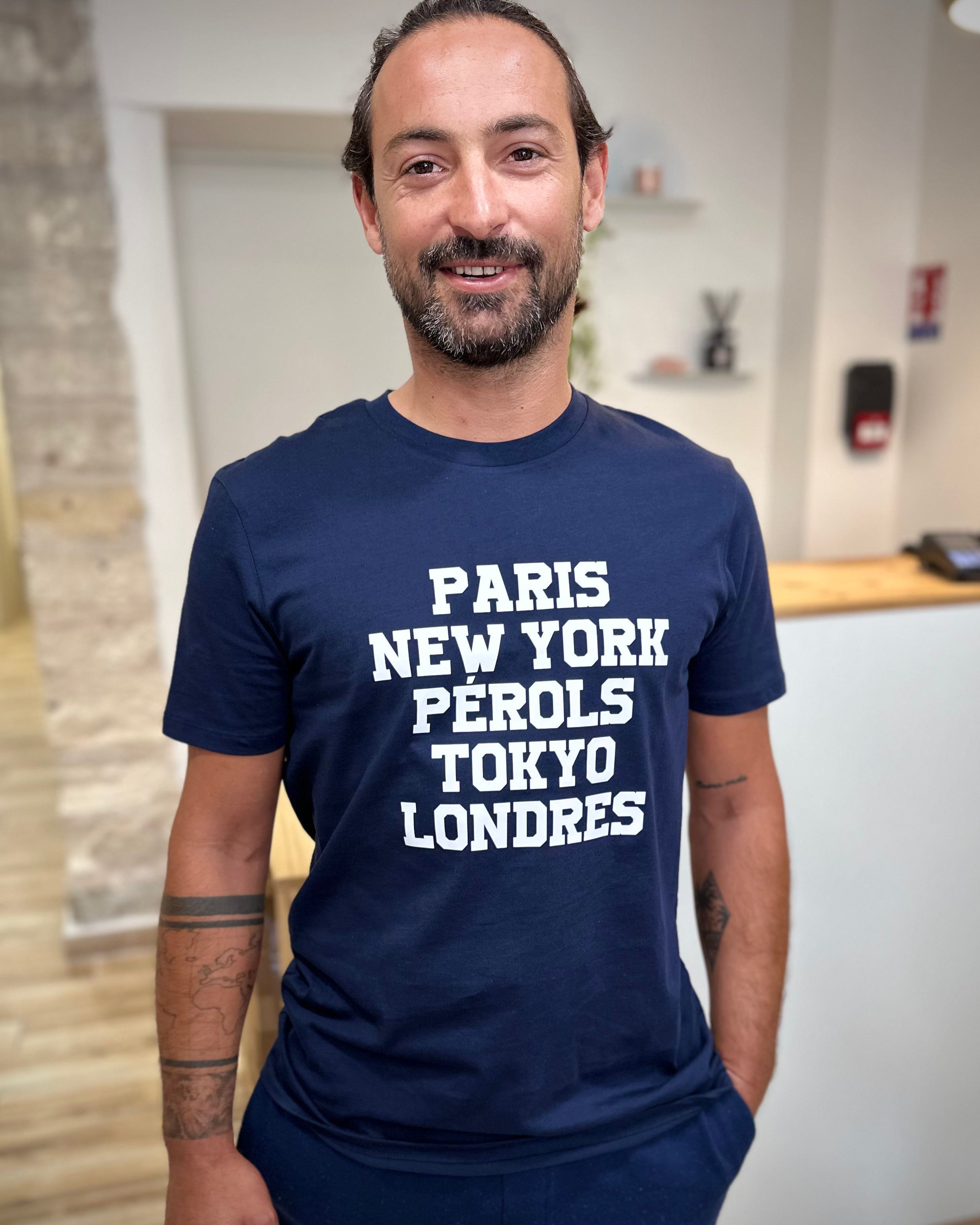 Homme portant un tee-shirt bleu marine imprimé blanc Paris New-York Pérols Tokyo Londres