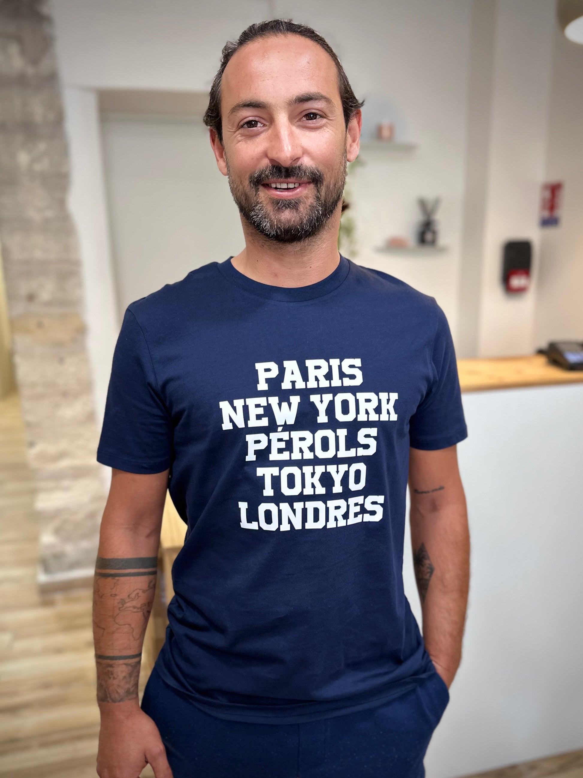 Homme portant un tee-shirt bleu marine imprimé blanc Paris New-York Pérols Tokyo Londres