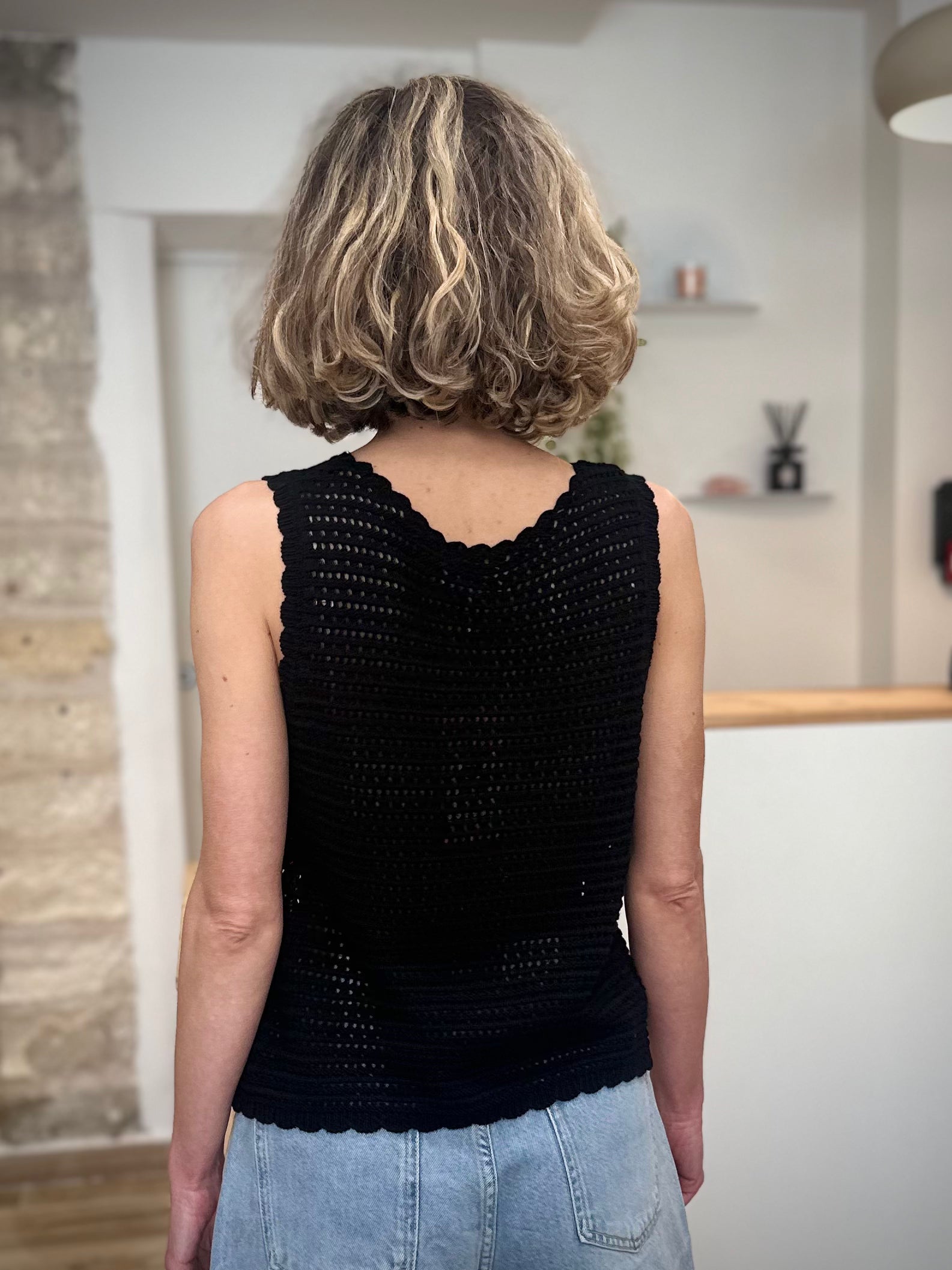 Femme de dos portant un top en maille ajourée noire 
