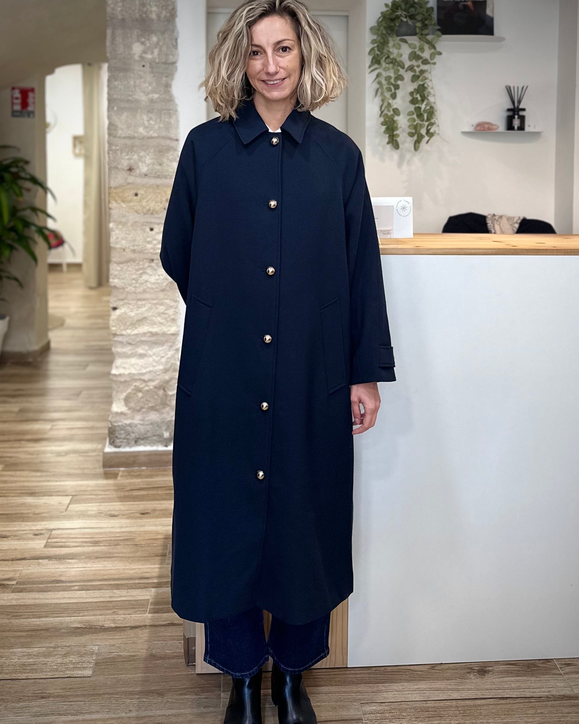 Femme portant un trench long bleu marine à boutons dorés