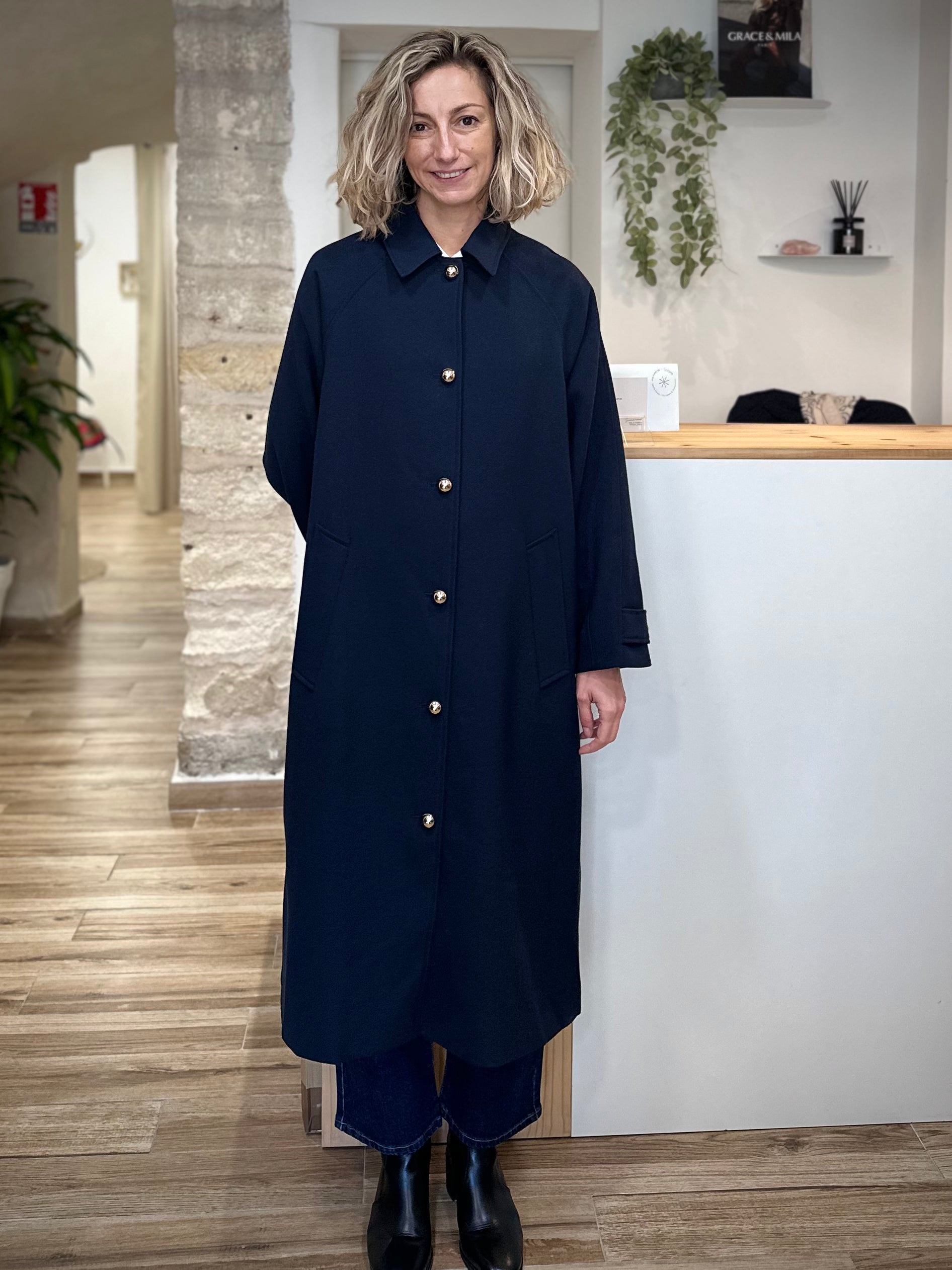 Femme portant un trench long bleu marine à boutons dorés