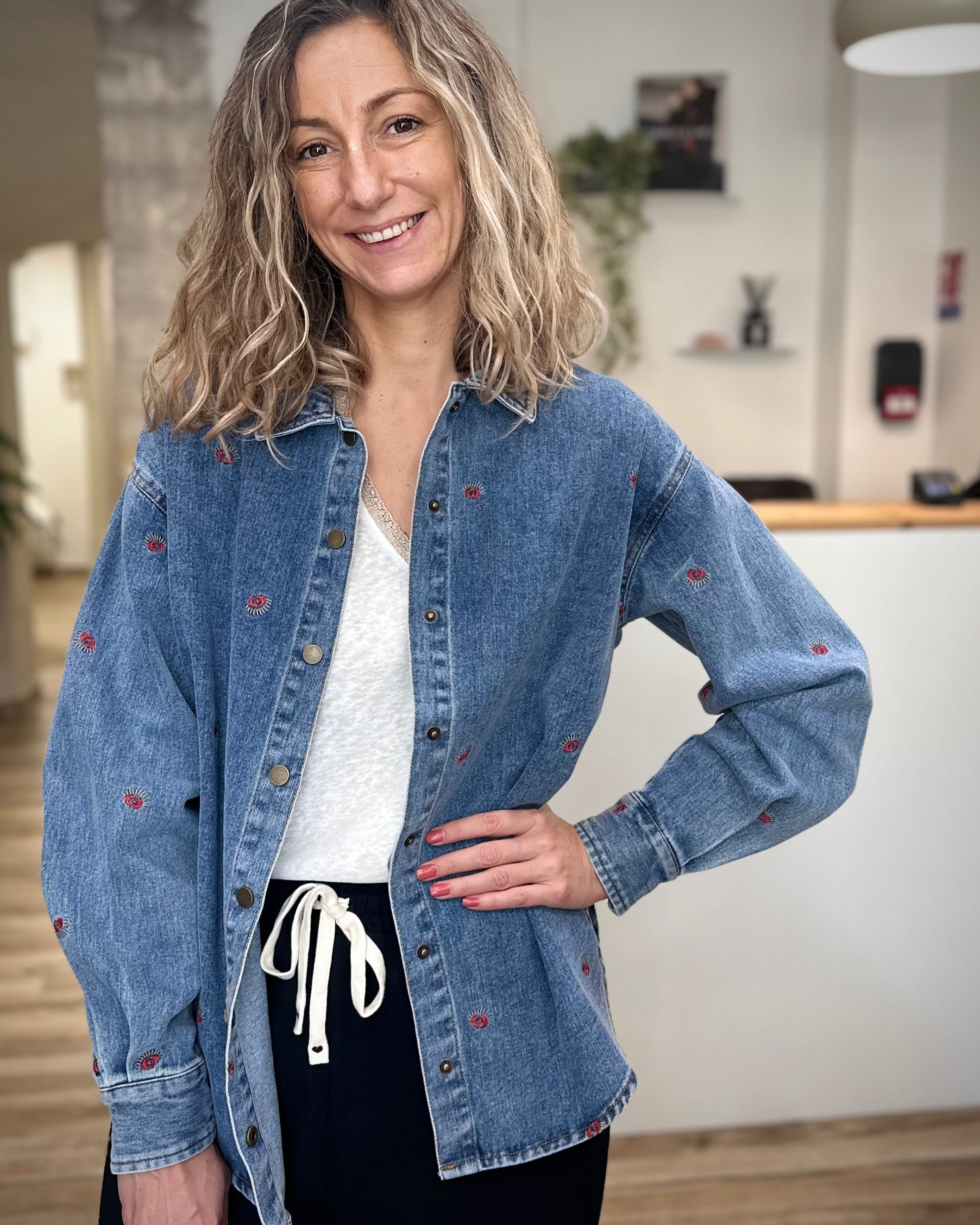 Femme portant une veste en jean oversize brodée motif œil rouge