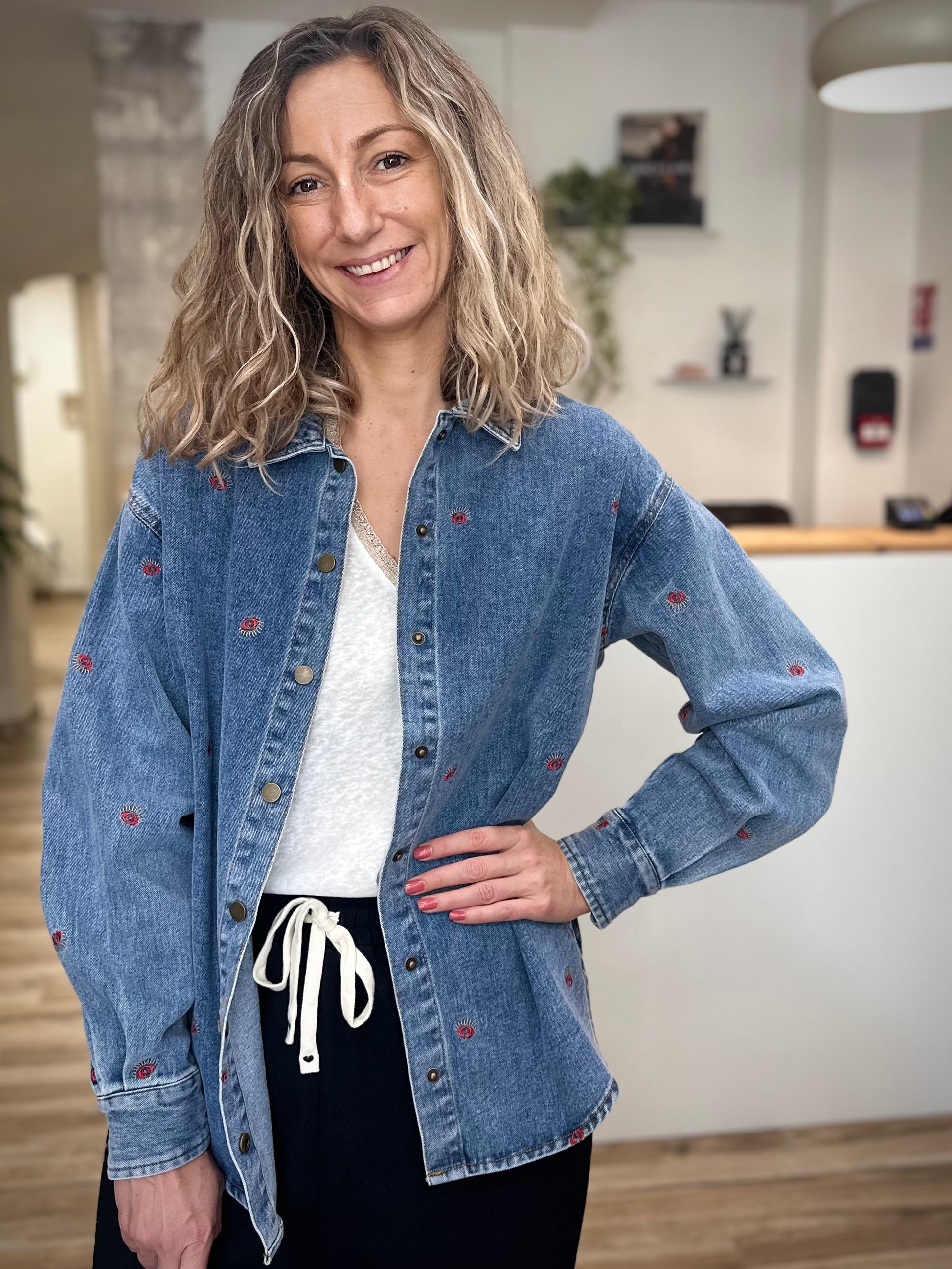Femme portant une veste en jean oversize brodée motif œil rouge